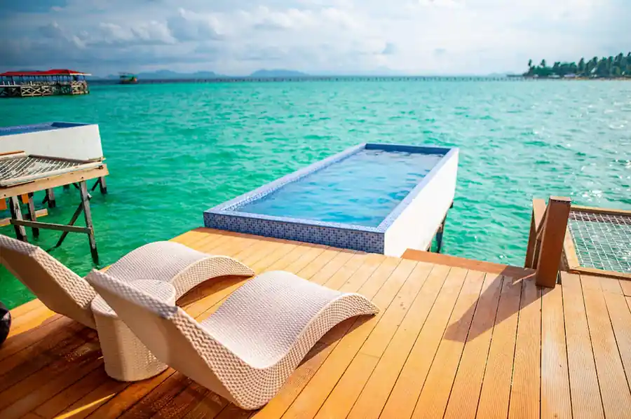 Private wooden deck with an infinity plunge pool and sun loungers overlooking the ocean at the Family Room in Turtle Seaweed Resort.